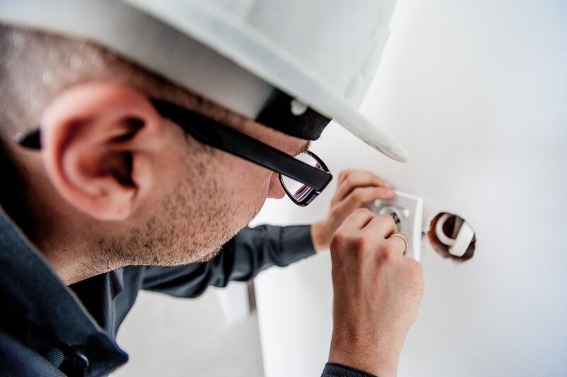 Electrician in glasses is adjusting a wall outlet (picture taken with Nikon D700 and Nikon AF-S 17-35mm F2.8 IF ED )