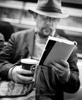 Man is reading book and drinking coffee on the subway