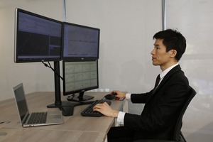 A trader at a desk with three monitors and a laptop