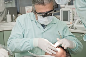 A dentist is examing a male patient