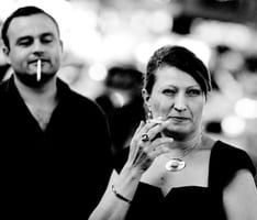 Guy that smokes is looking at a lady that also smokes
